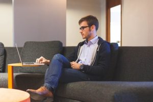 man on couch using laptop