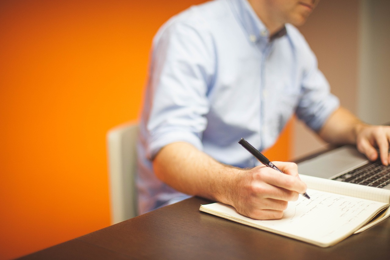 man using laptop and holding pen